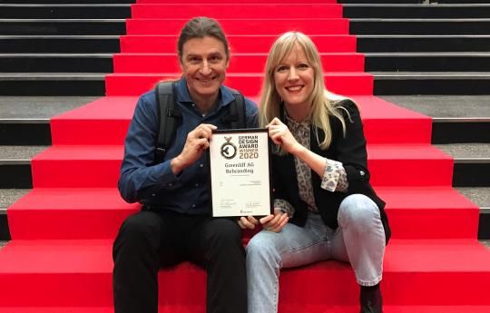 Zwei Greenliff Mitarbeiter sitzen auf einer Treppe mit rotem Teppich und freuen sich über die Auszeichnung vom German Design Award.